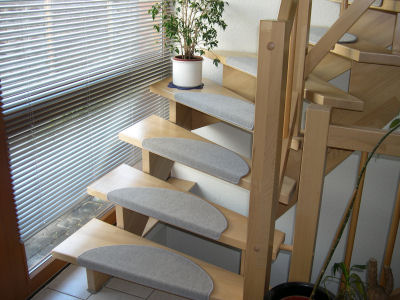 Holztreppe mit hellgrauen Stufenmatten